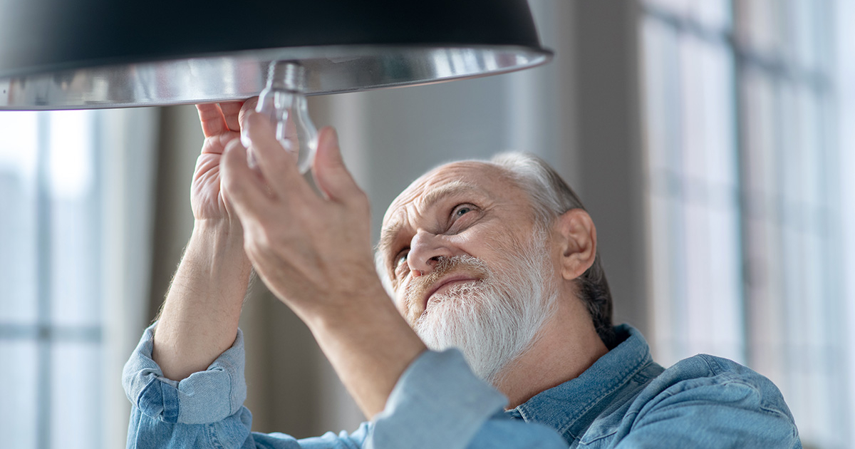 man putting light bulb into lamp