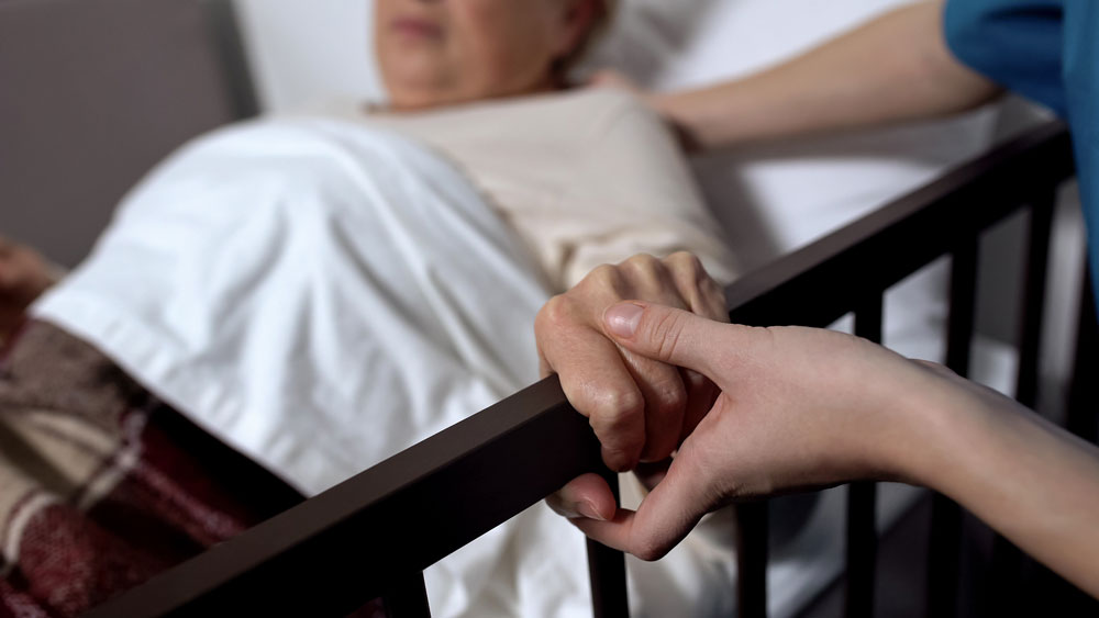 senior lady in bed holding onto hand rail