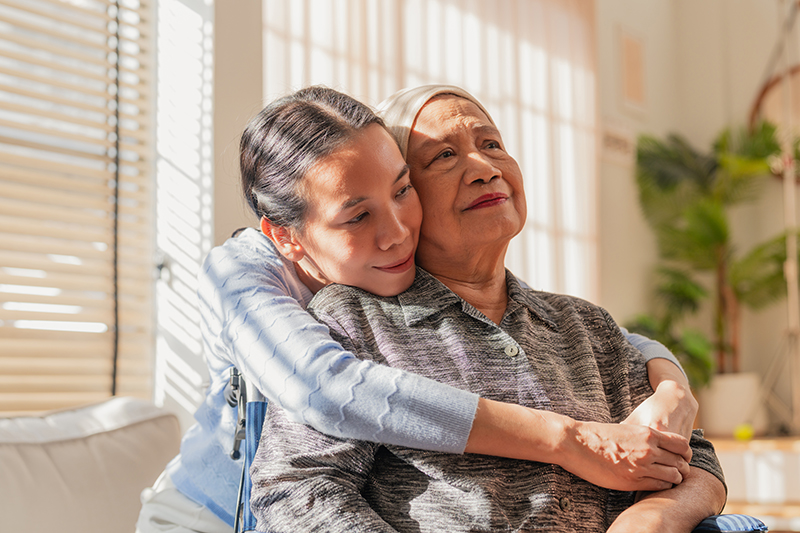 adult daughter hugging her senior mother with cancer