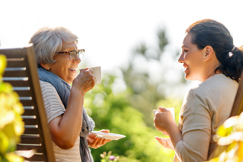 An older woman smiles while enjoying her morning cup of tea, happy that she knows what it’s really like to have a live-in caregiver.