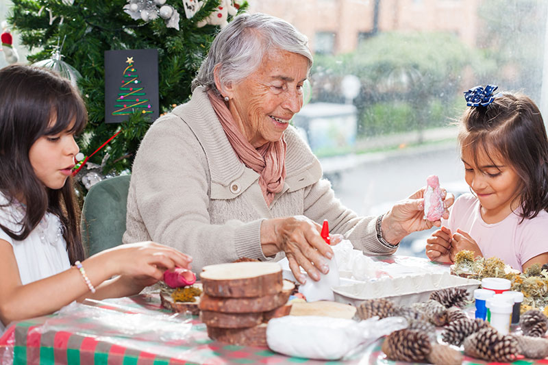 A woman smiles as she enjoys making story ornaments, one of the best holiday activities for someone with dementia.