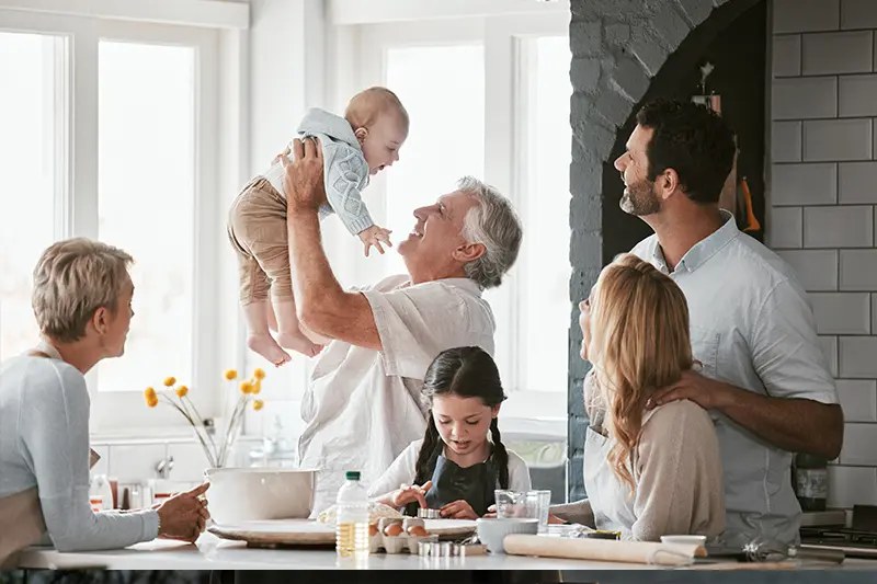 A family celebrates their shared family living situation with smiles and laughter in the kitchen.